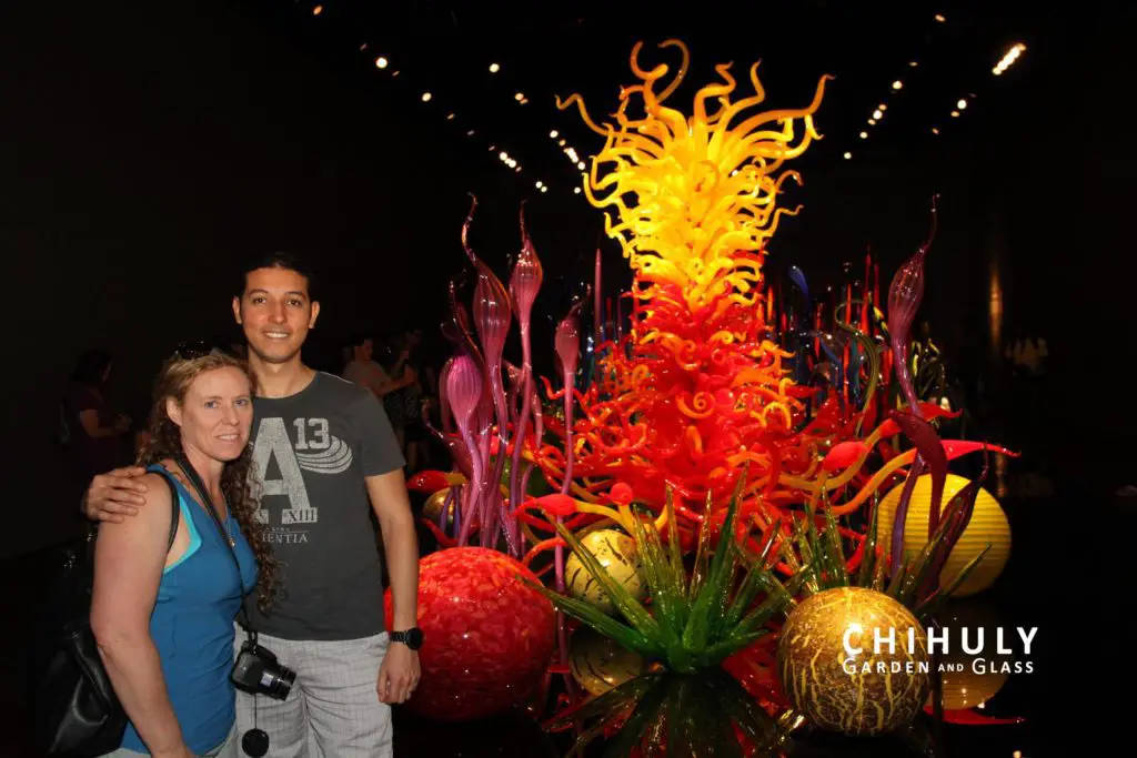 standing beside a giant red and yellow glass sculpture at Chihuli Garden and Glass Seattle