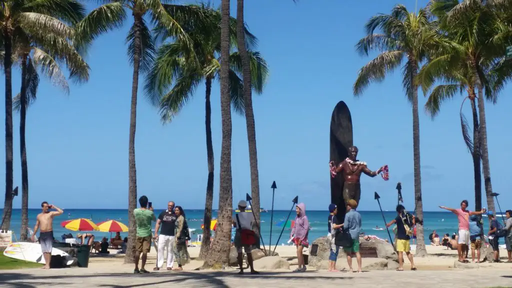 hawaii on a budget - kalakaua drive waikiki with palm trees and statue of Duke