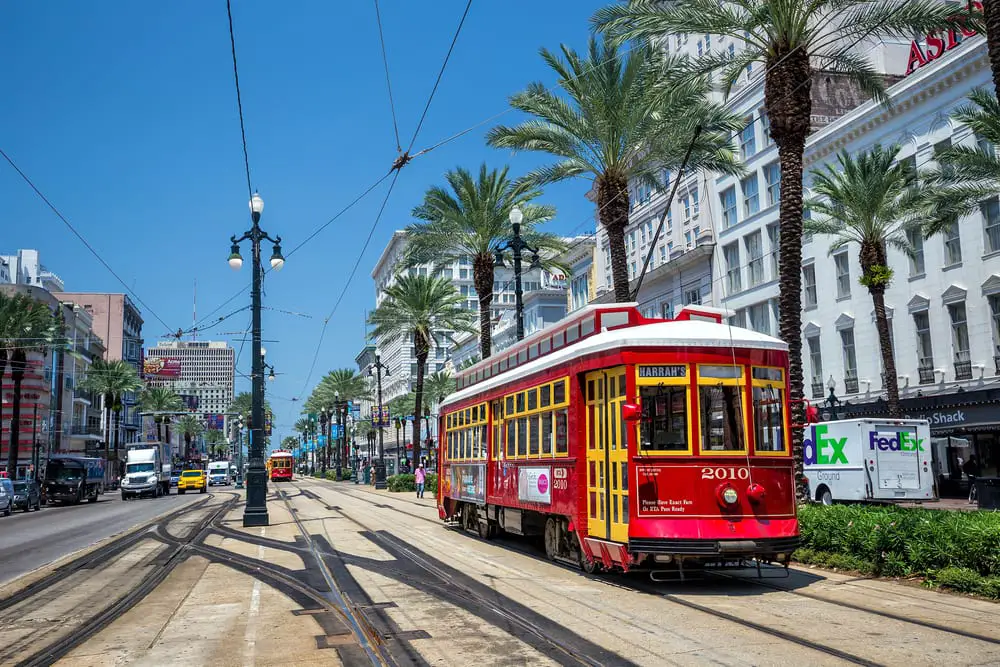 travel USA on a budget = New Orleans tram in the street with cars driving along side