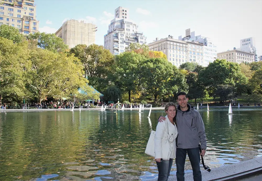 view of central park over the lake with city buildings in the background