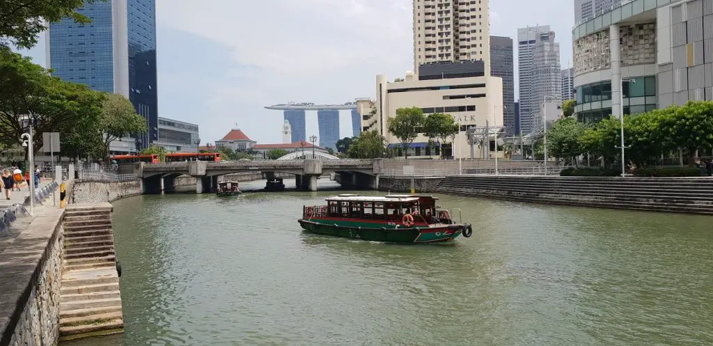 best area to stay in Singapore - bumboat on the Singapore RIver with Marina bay Sands in the back ground