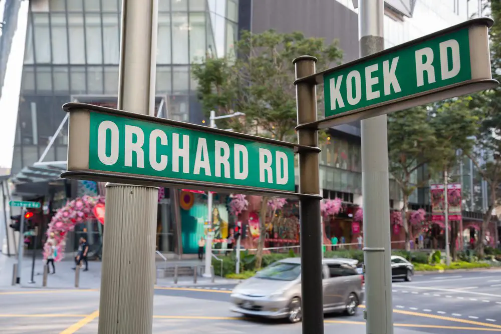 best area to stay in singapore - a street sign showing direction of Orchard road