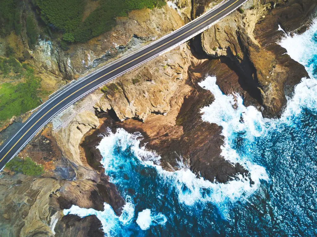 Hawaii on a budget - overhead shot of coastal raod and crashing waves against rockes