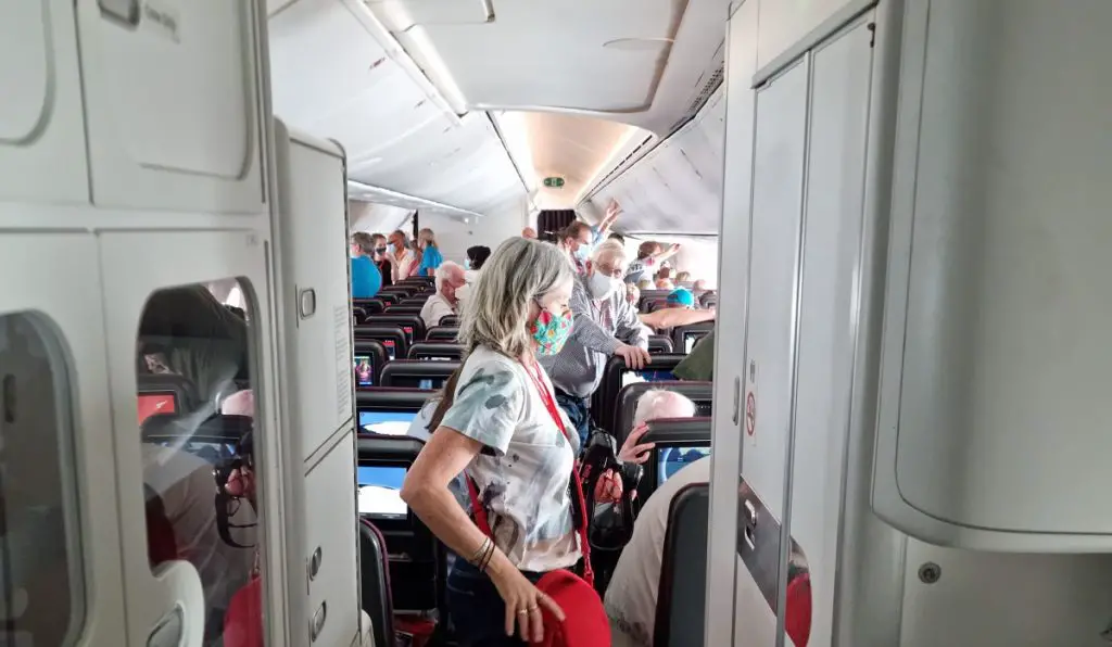 qantas to Antarctica flight review.
Shows passengers in the aisle looking outside the cabin windows.