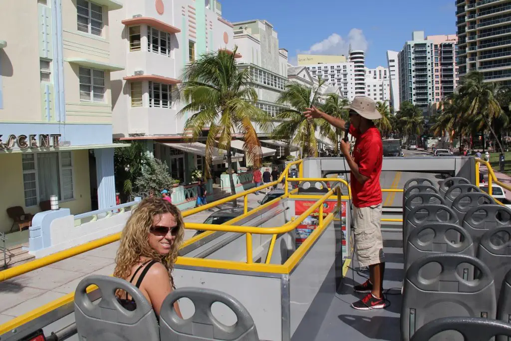sitting on open air bus in Miami with tour guide pointing to historic buildings