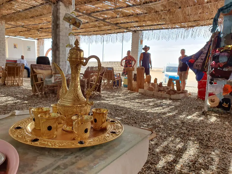 A bedouin tent of rugs and chairs and a gold tea set in the foreground. Things to do in Egypt