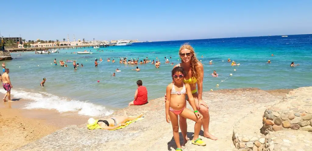 standing on the edge of the blue waters of the Red Sea with people enjoying the sunny day in the water