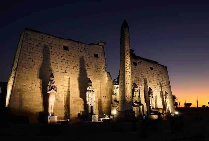 Luxor temple at night illuminated. temple with statues in a line and sunset in the background. Egypt experiences