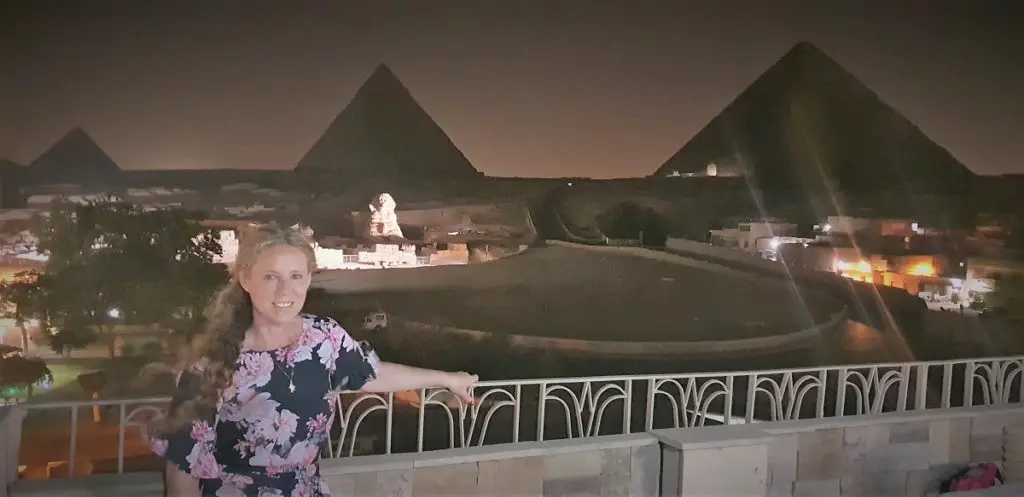 standing on a hotel blcony with the Pyramids of Giza at night in the background - Egypt 2 week itinerary