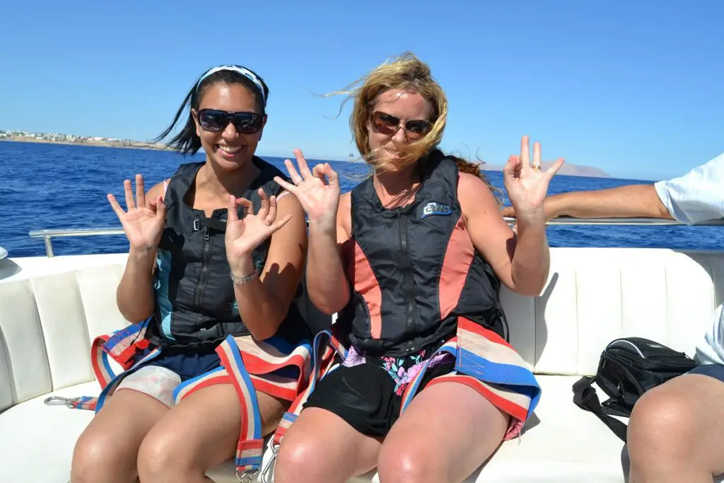 Two girls on a boat smiling before going parasailing in Naama Bay.