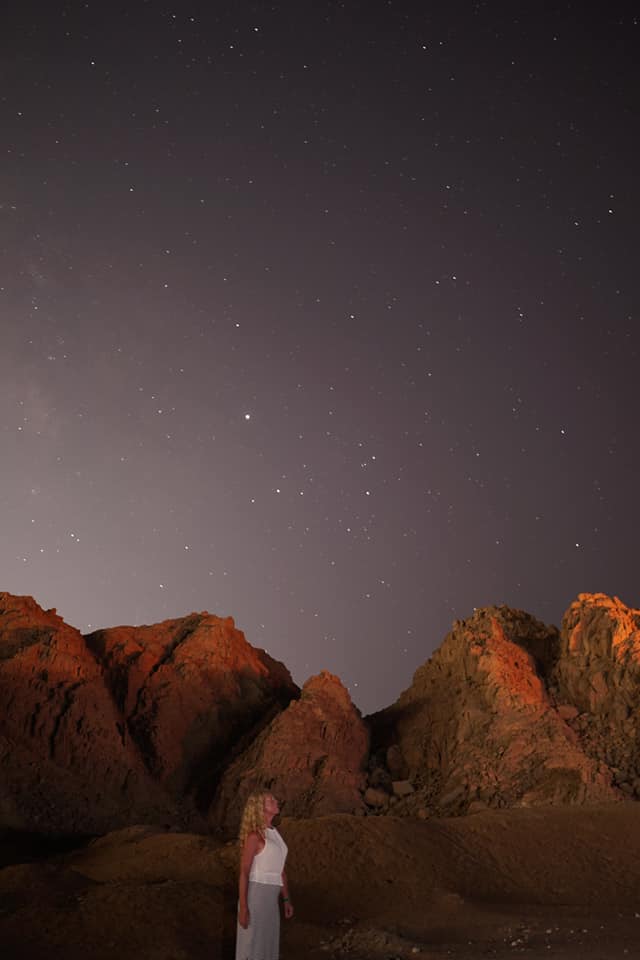 Egyptian desrt at night with twinkling stars and lady looking up to the sky