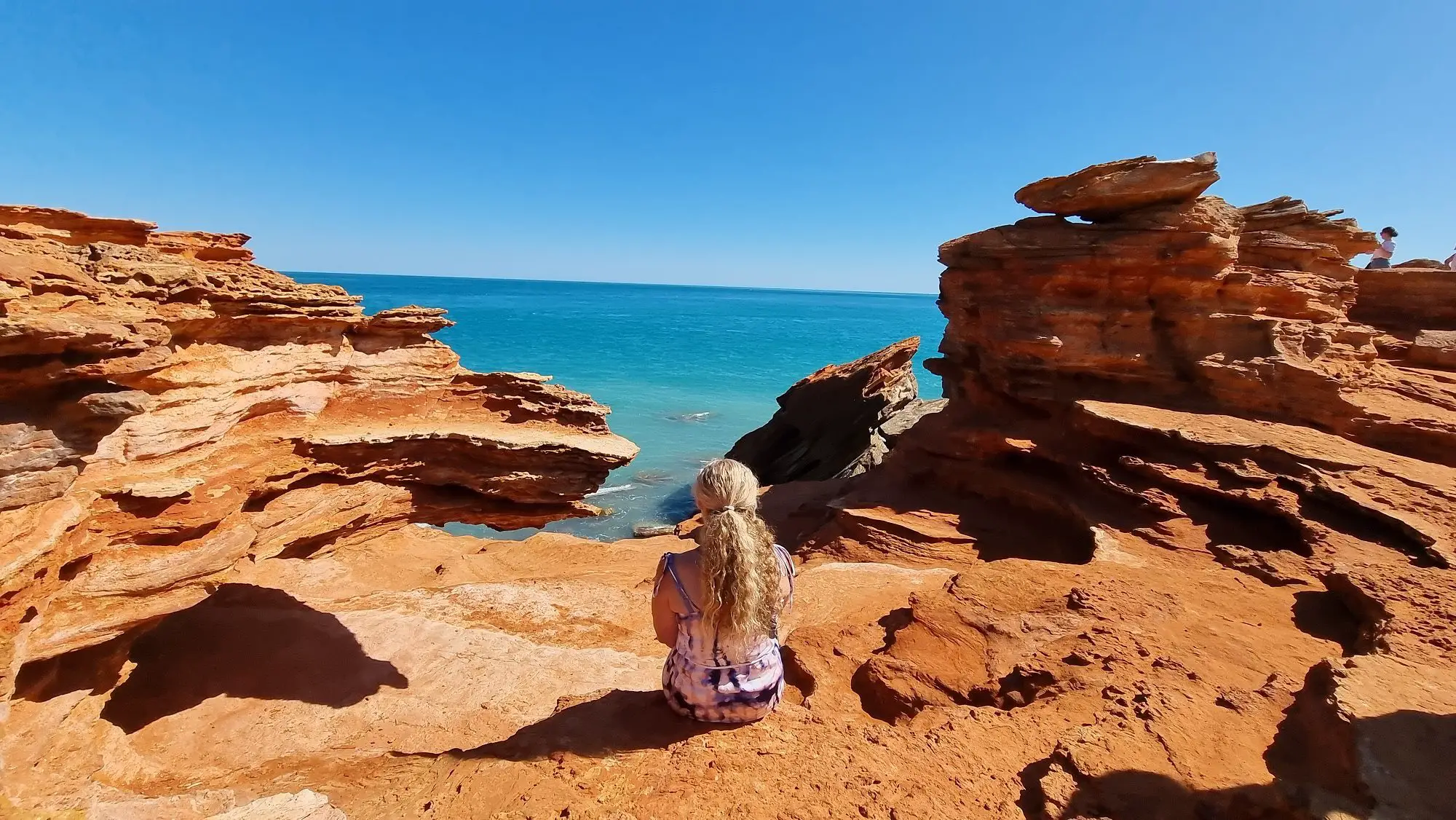 sitting on red rocks overlooking the ocean in Broome