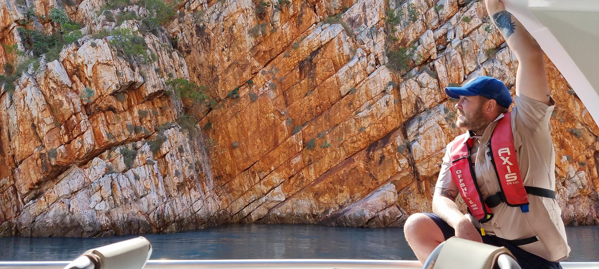 red rock wall with our guide sitting on the edge of the boat