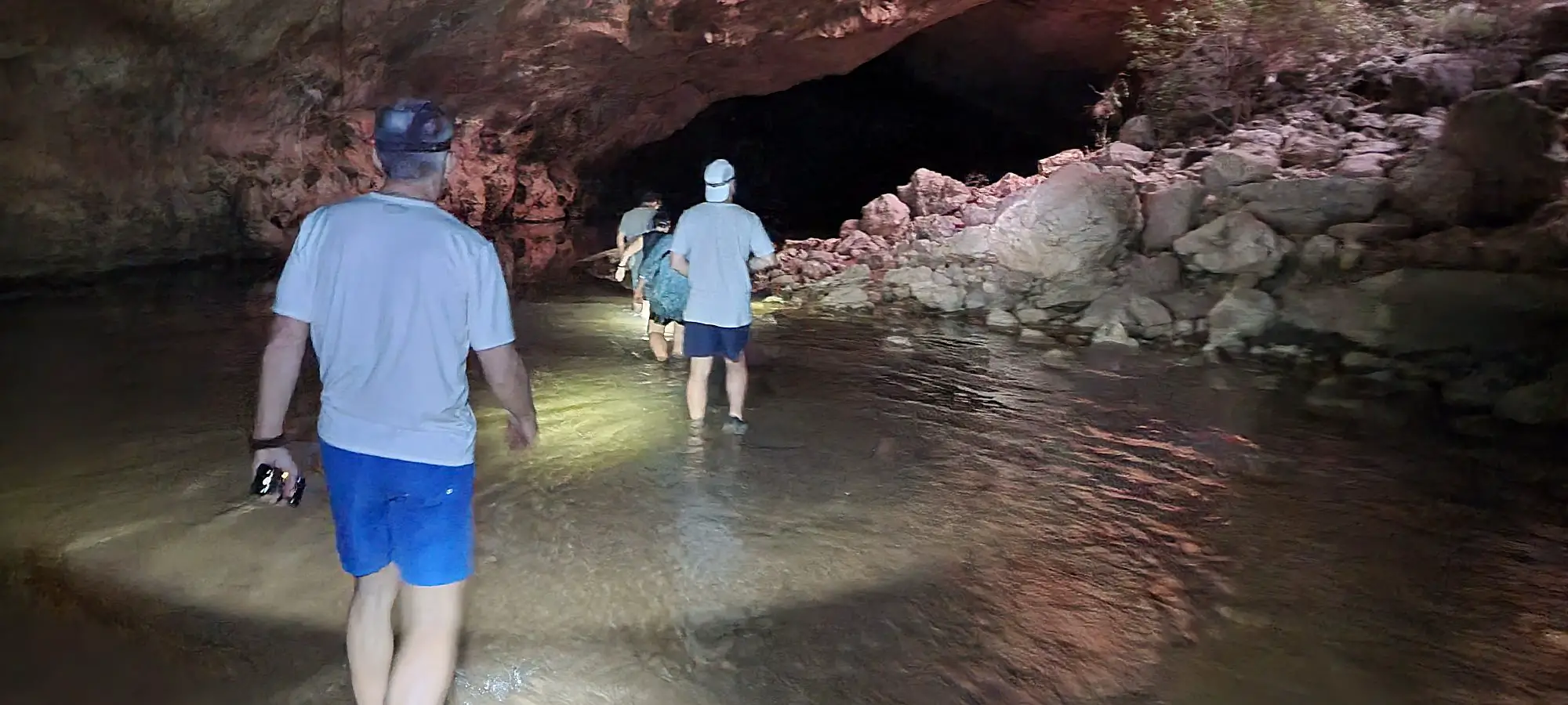 Tunel creek Kimberley's show people wading through water in the darkness with head torches on