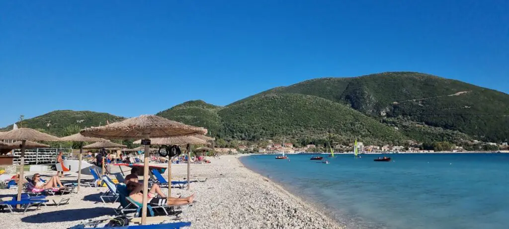 beach with people on sun lounges and mountains in the background